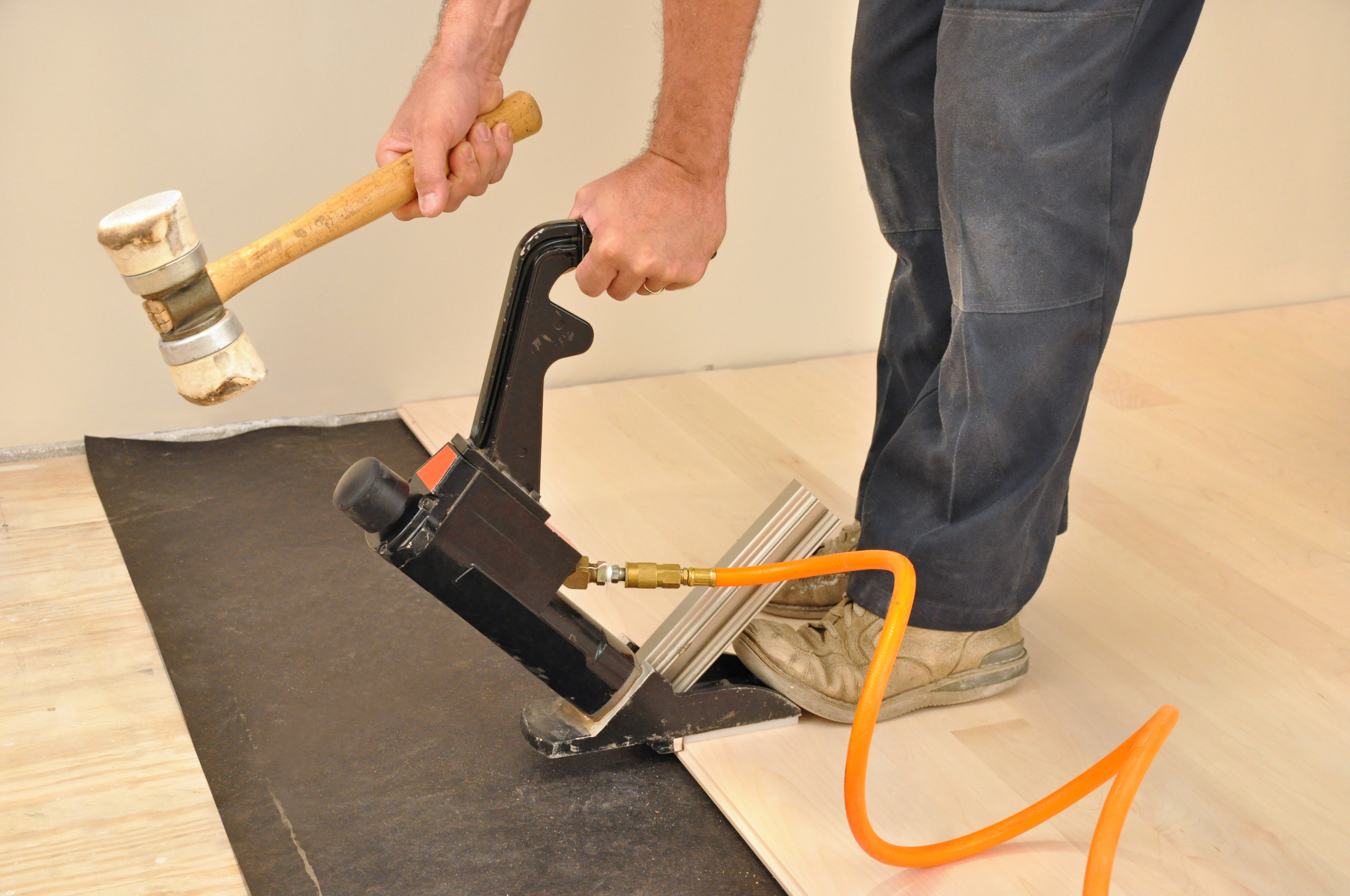 Flooring Install America, Inc Man installing hardwood flooring with a